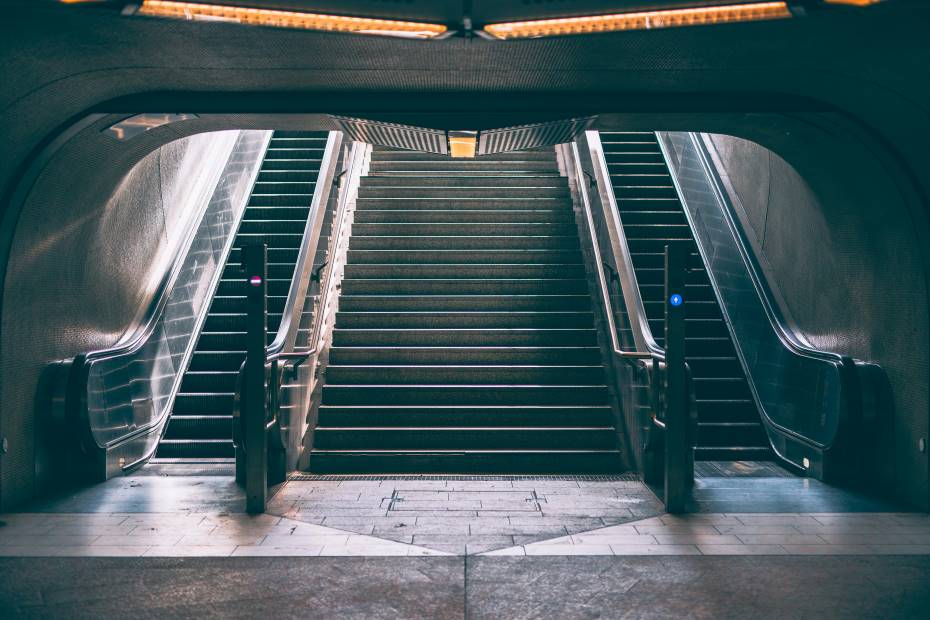 Das Bild zeigt eine Treppe, an beiden Seiten Rollentreppen, die nach oben führt.